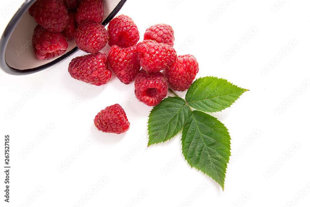 White cup with ripe raspberries and green leaf isolated on white background. White cup with ripe raspberries and green leaf isolated on white background.