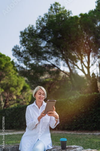 Mature woman using on tablet while resting at the park