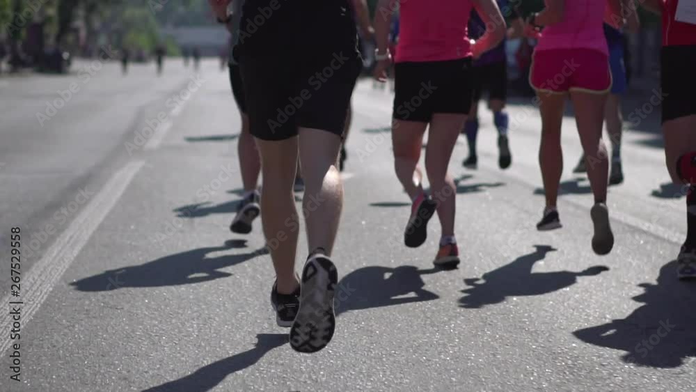 Participants of the marathon run along the road on a city street on a sunny spring day. Legs close-up. Sport and healthy lifestyle. Run at the marathon Participants of the marathon run along the road on a city street on a sunny spring day. Legs close-up. Sport and healthy lifestyle. Run at the marathon