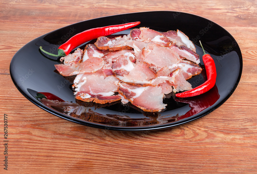 Thin slices of dried pork and chili on black dish Thin slices of dried pork and chili on black dish