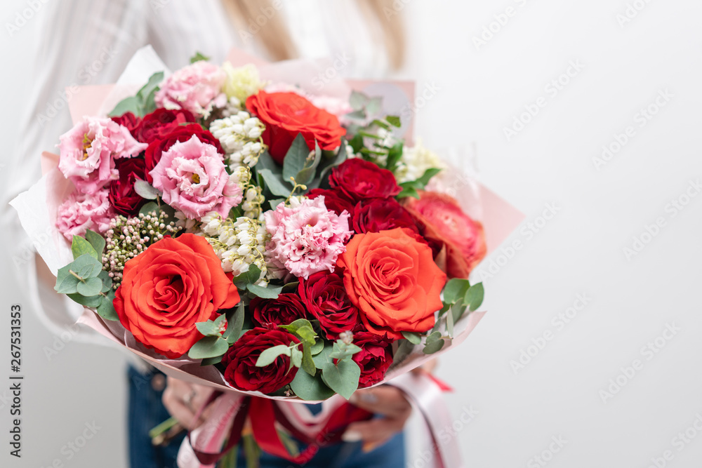 Beautiful bouquet of mixed flowers in womans hands. the work of the florist at a flower shop. Delicate Pastel color. Fresh cut flower. Red and pink color