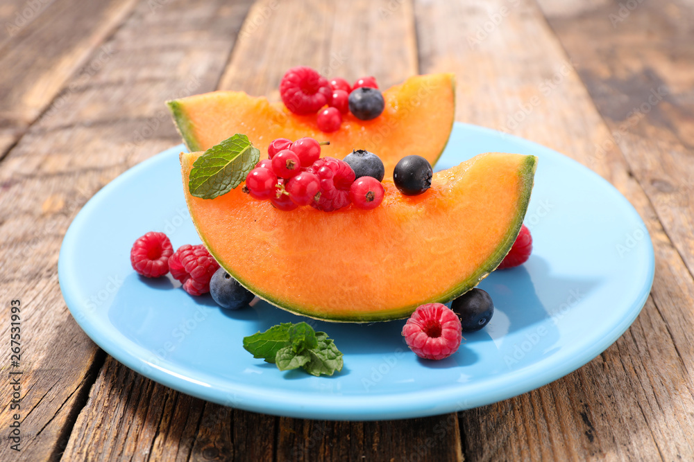 melon with berries fruits on wood background