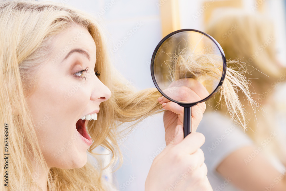 Happy woman looking through magnifer at hair Happy woman looking through magnifer at hair