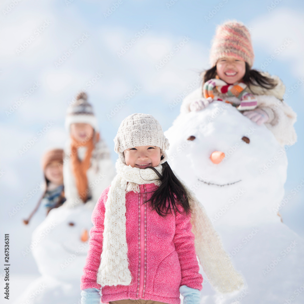 雪だるまの周りで微笑む小学生