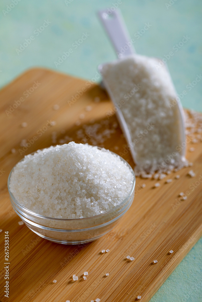 Sugar in glass bowl on wooden background Sugar in glass bowl on wooden background