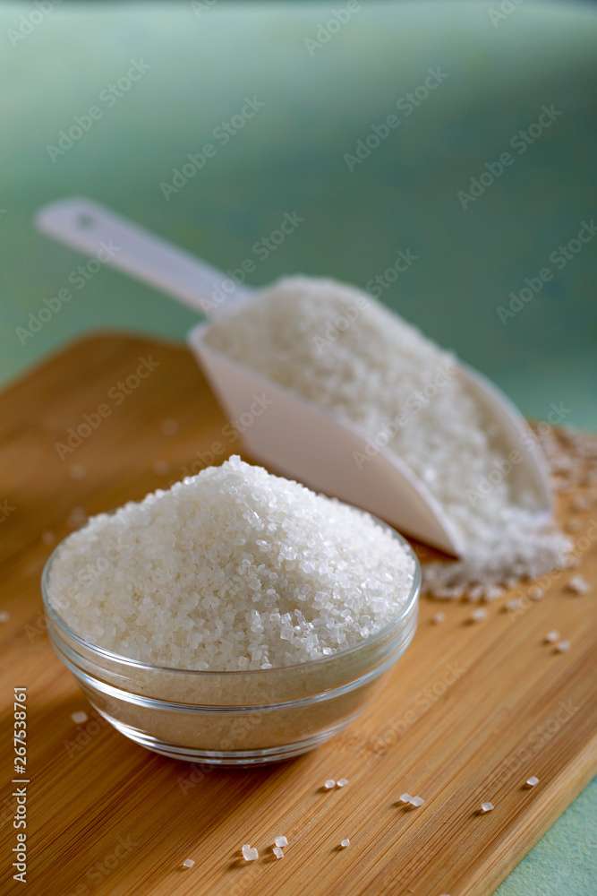 Sugar in glass bowl on wooden background Sugar in glass bowl on wooden background