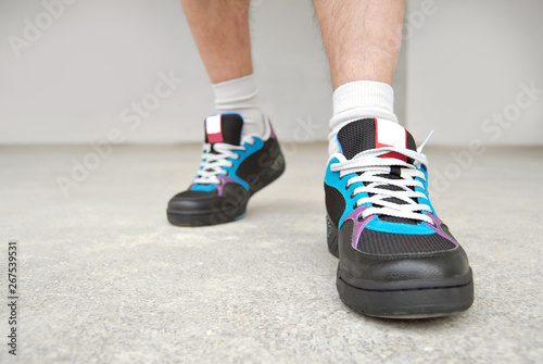 A man in shorts and sneakers goes on a marble tile. Close-ups of sneakers on the background of a gray wall.
