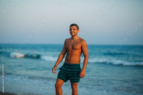 Handsome man walking on the coast in sunset. Background of beautiful sea