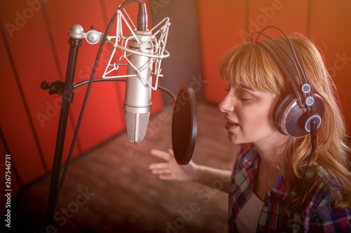 Female with microphone recording a voice for dubbing in music studio photo