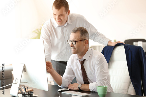 Handsome mature businessman with colleague working in office