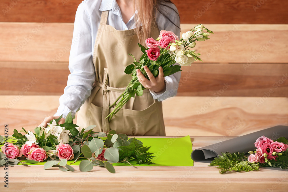 Florist making bouquet at table against wooden background Stock Photo