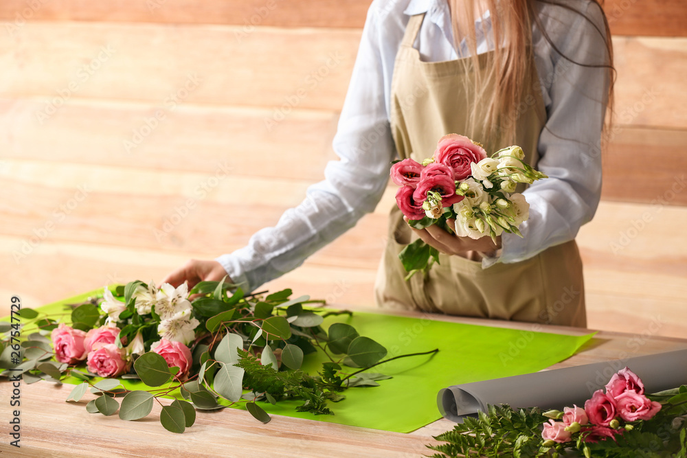 Florist making bouquet at table against wooden background Stock Photo