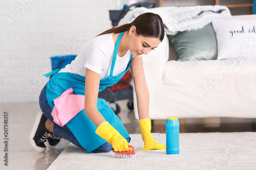 Female janitor cleaning carpet in flat