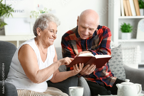 Portrait of senior couple reading book at home