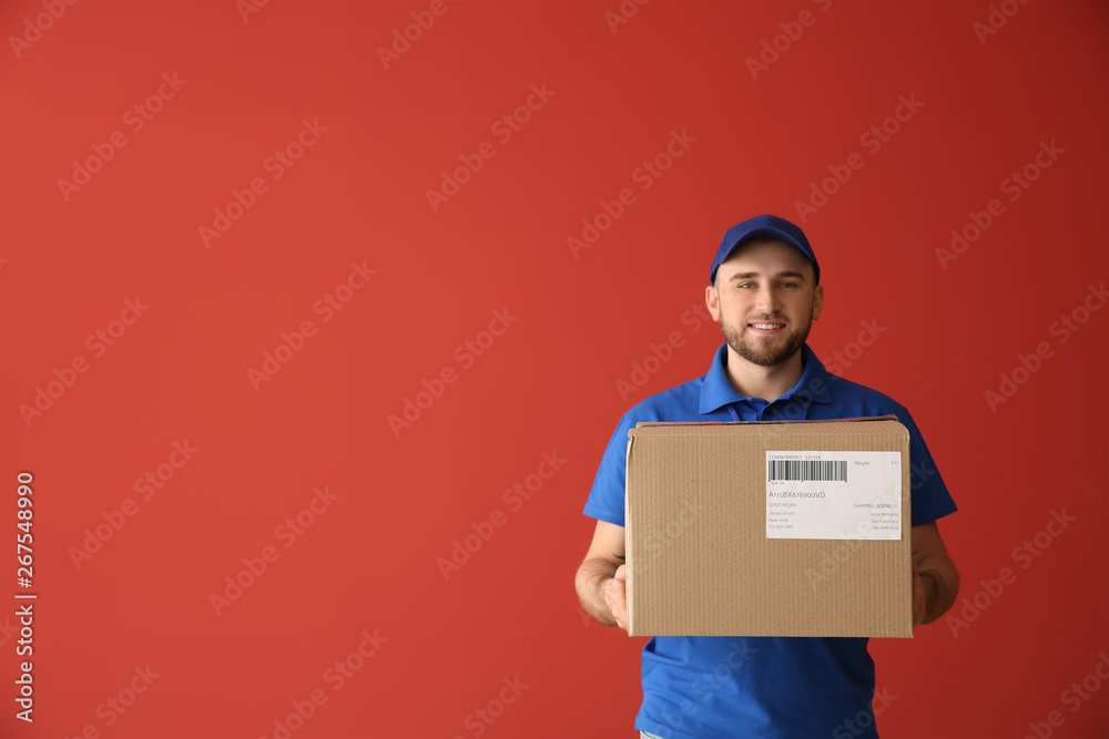 Handsome delivery man with box on color background Handsome delivery man with box on color background