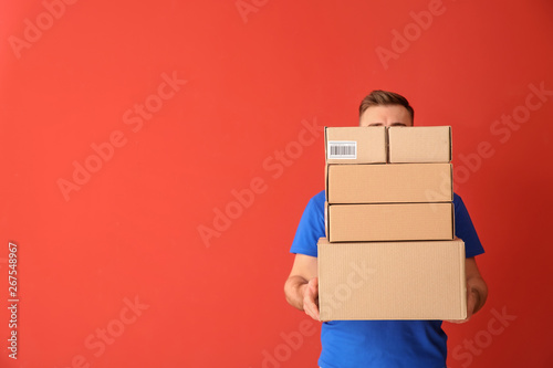Delivery man with boxes on color background photo