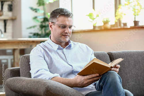 Handsome mature man reading book at home