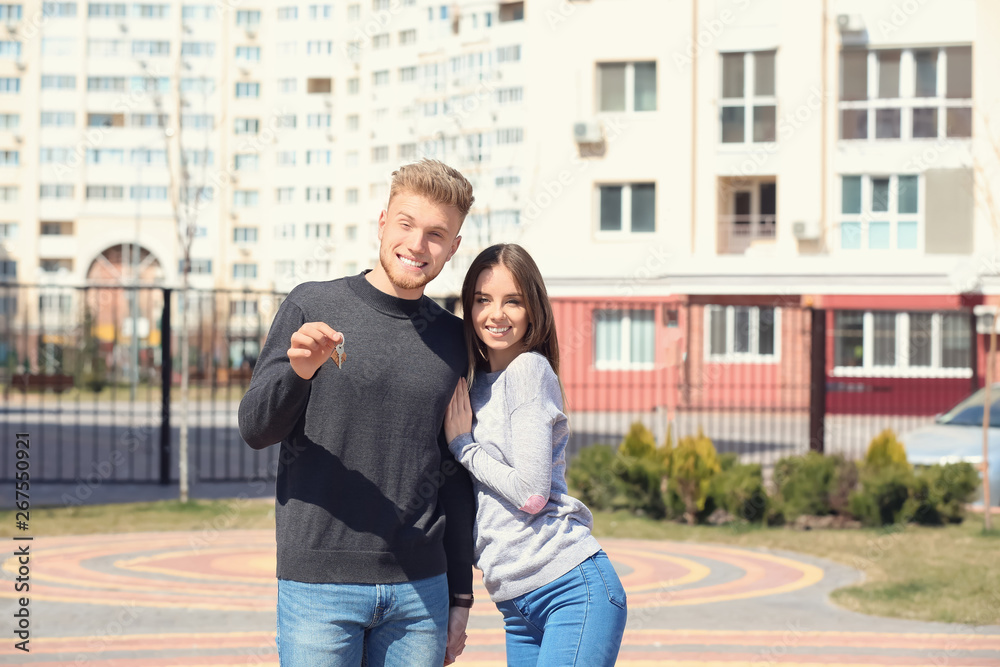 Young couple with key near their new house outdoors