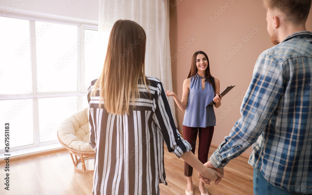 Fototapeta premium Real estate agent showing young couple a new house