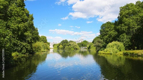 View on duck lake or pond at St James's park on sunny summer day with birds swimming in green lush foliage of willow trees in London, United Kingdom photo