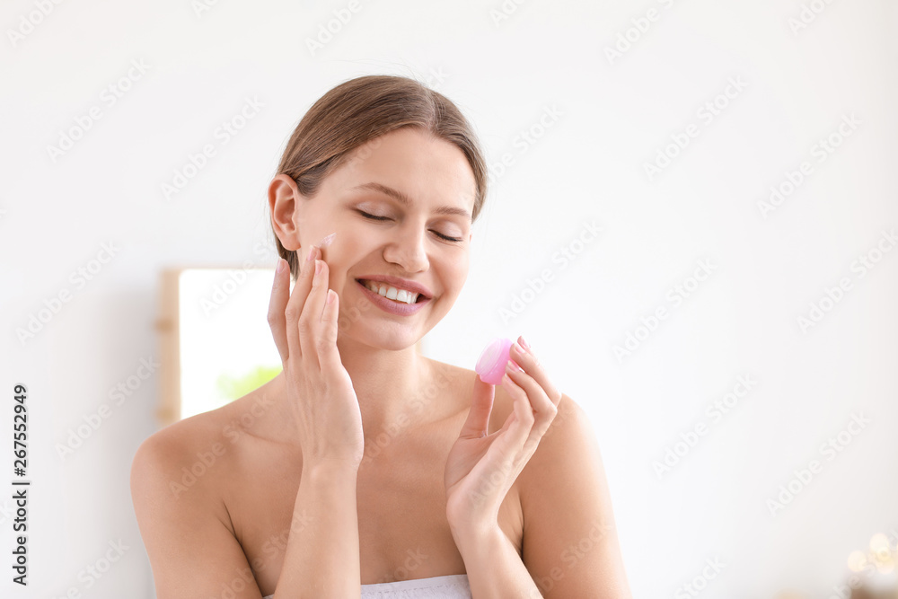 Beautiful young woman applying cream at home Beautiful young woman applying cream at home