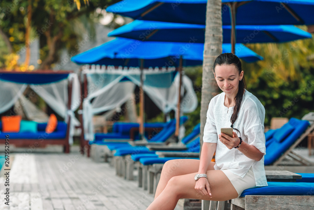 Young woman on white sand and talking by her phone