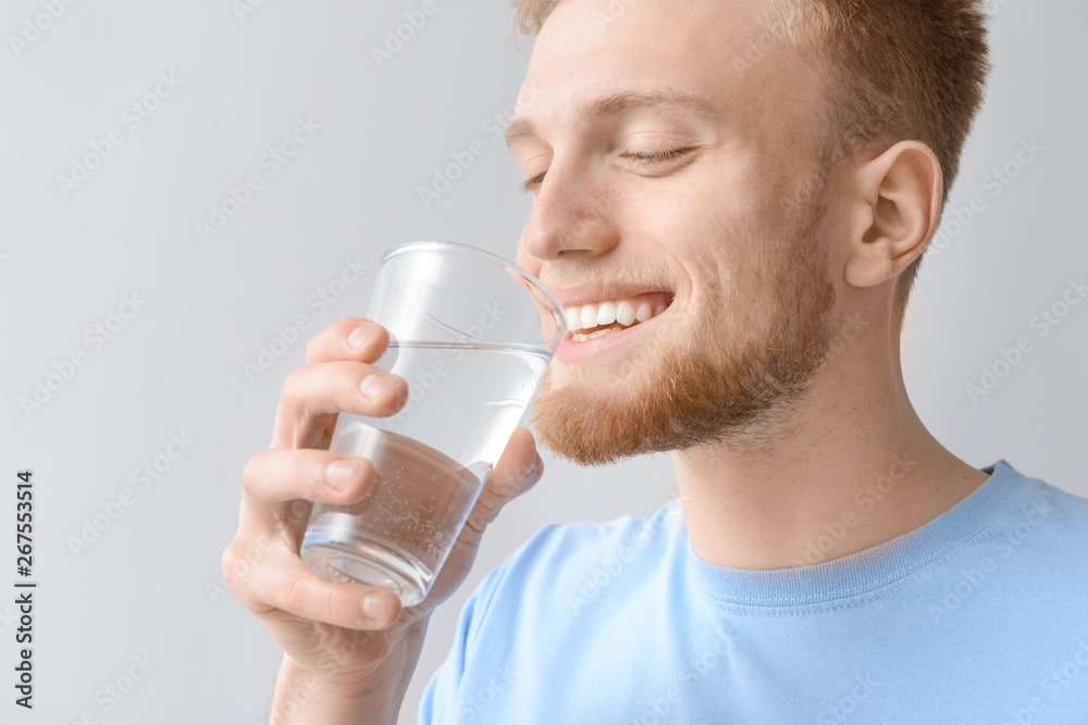 Man with glass of fresh water on light background Man with glass of fresh water on light background