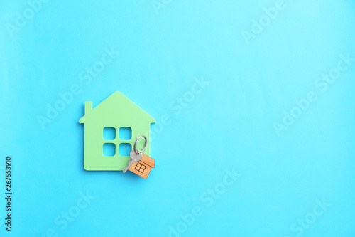 Figure of house and key on color background