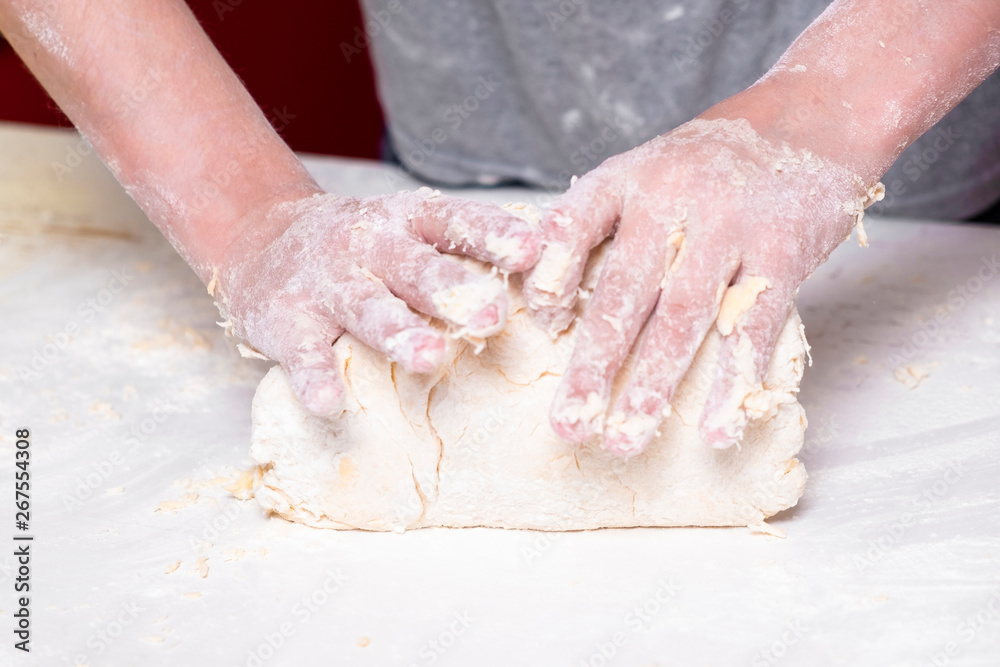 Teen hands preparing dough for baking on white table close up