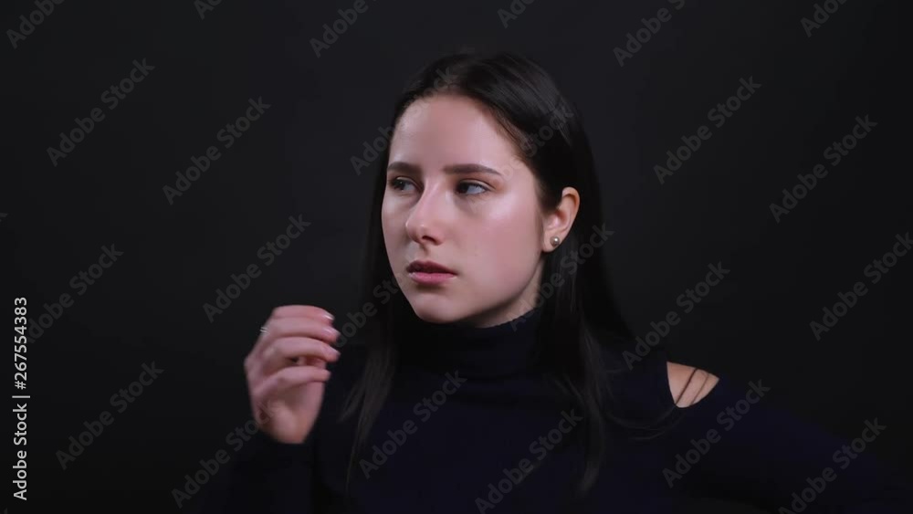 Closeup portrait of young attractive brunette female being angry and frustrated looking at camera with background isolated on black Closeup portrait of young attractive brunette female being angry and frustrated looking at camera with background isolated on black