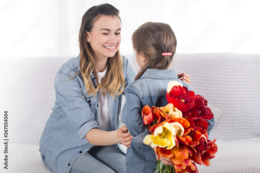 Mother's day. Little daughter with flowers congratulates her mother