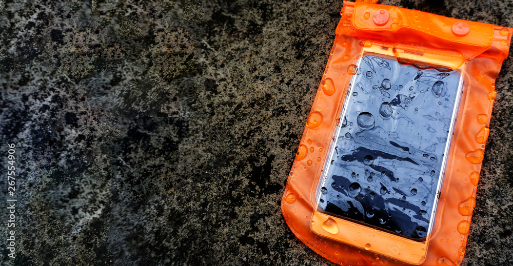 Orange waterproof mobile phone case with water droplets on texture background.PVC zip lock bag protect mobile phone or important items from water.Concept for Songkran water festival in Thailand. Orange waterproof mobile phone case with water droplets on texture background.PVC zip lock bag protect mobile phone or important items from water.Concept for Songkran water festival in Thailand.