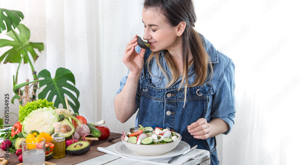 Young and happy woman eating salad at the table