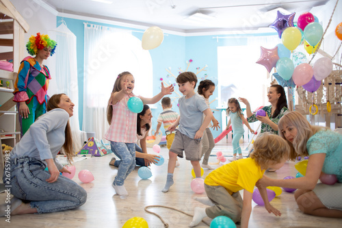 Happy children and their parents entertain and have fun with color balloon on kids birthday party