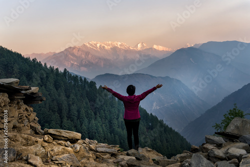 Women, travelers, standing, arms, fresh air in the sunrise on the way to the lake gosaikunda On the langtang mountain range Of Nepal With mountains and forests in the foreground photo
