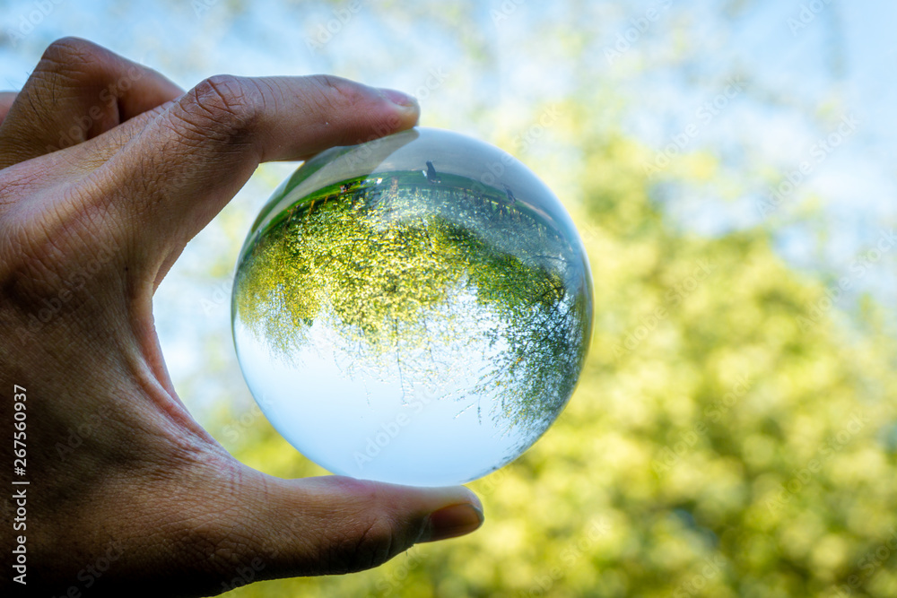 A hand holding a crystal ball for optical illusion. Known as an orbuculum, is a crystal or glass ball and common fortune telling object. Performance of clairvoyance and scrying A hand holding a crystal ball for optical illusion. Known as an orbuculum, is a crystal or glass ball and common fortune telling object. Performance of clairvoyance and scrying