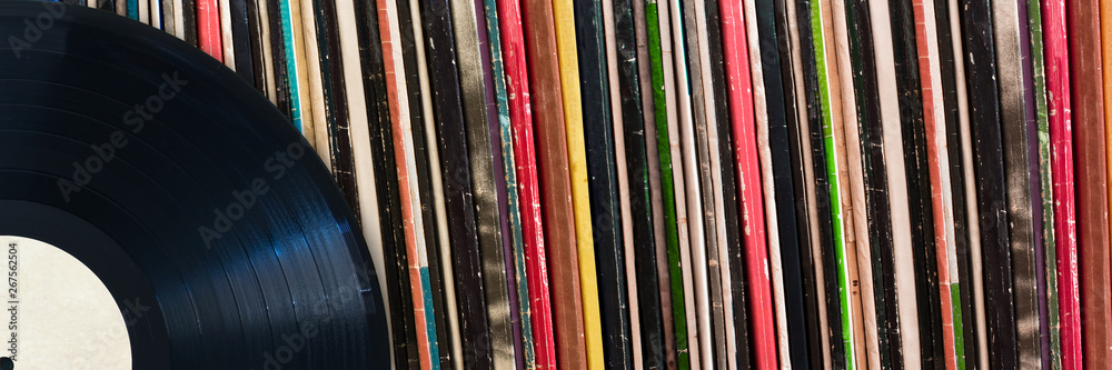 Vinyl record in front of a collection of albums, vintage music concept web banner
