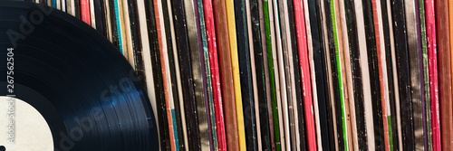 Vinyl record in front of a collection of albums, vintage music concept web banner photo