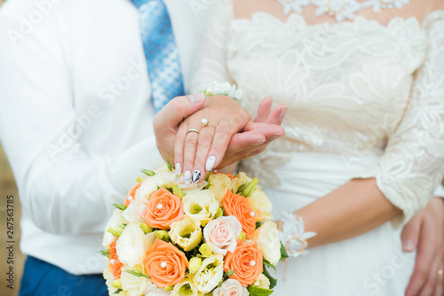 Hands of groom and bride with wedding rings and flowers roses. concept of love and marriage.