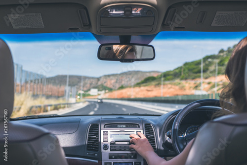 The girl is driving on the highway in Australia. View from the back seat of the car on the windshield, road and the driver
