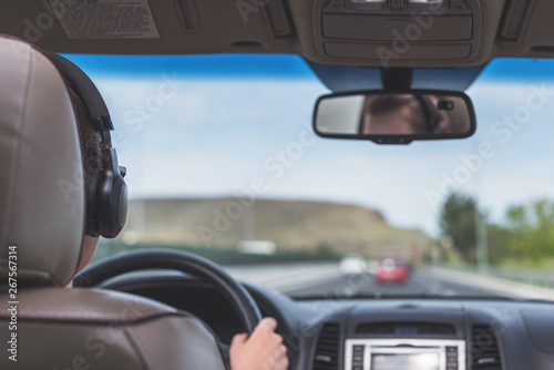 The girl in the headphones is driving on the highway in California. View from the back seat of the car on the windshield, road and the driver
