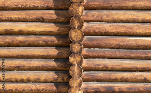 Wooden texture of sanded logs with an end wall and a vertical row of sawn trunks
