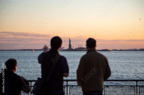Statue of Liberty New York. People looking at famous Statue of Liberty monument. Beautiful sunset skyline view from Battery Park, FiDi, Lower Manhattan Downtown. © theartofpics