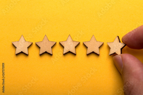 Hand putting wooden five star shape on yellow background