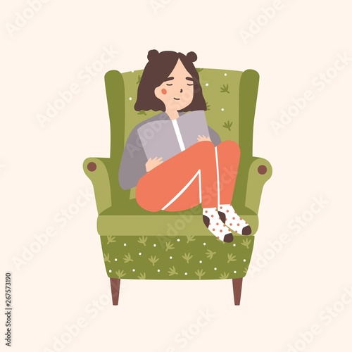Adorable girl sitting in comfy armchair and reading book isolated on light ba...