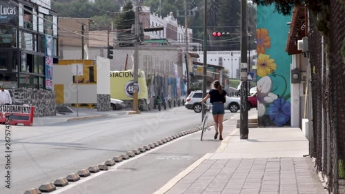 Wallpaper Mural Girl walking on paved road with a bike aside. Girl waling on a cycling line. Cycling lane in Cholula, Mexico. Torontodigital.ca