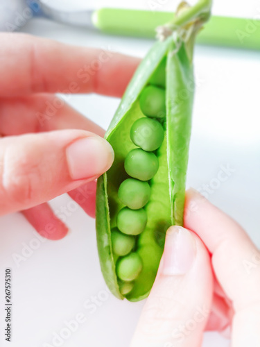 Young woman shelling fresh green peas