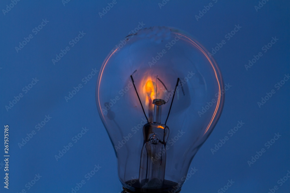 A dead electric light bulb with a burning matchstick behind it isolated on a clear background