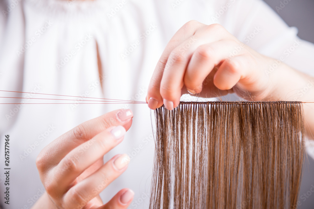 Obraz premium Dłonie młodej kobiety robiącej perukę