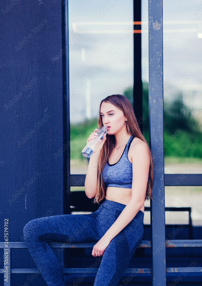 Fototapeta premium Shot of beautiful female runner standing outdoors holding water bottle. 